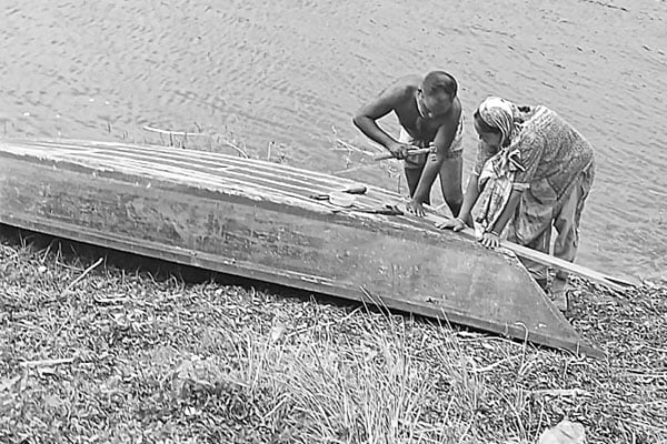 পুরনো নৌকা পরিচর্যায় ব্যস্ত কৃষক